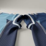 Macro close-up of an NFL-style jersey fabric showing crisp stitching and textured mesh under soft studio lighting.