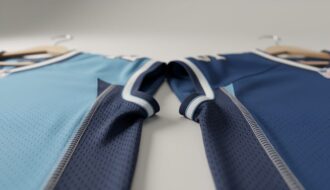 Macro close-up of an NFL-style jersey fabric showing crisp stitching and textured mesh under soft studio lighting.